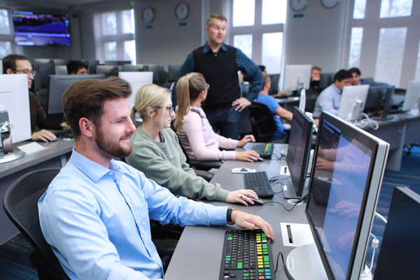 Professor teaching students in a classroom with computers